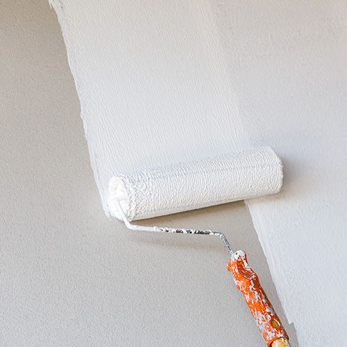 Painting contractors. Commercial Painters. White paint being rolled onto a wall.